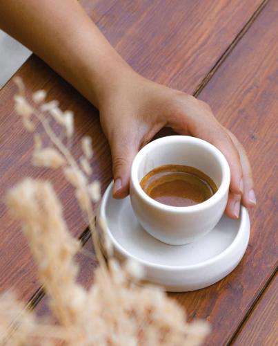 a person holding a cup of coffee on a table at XTILU Hotel - Adults only - in Oaxaca City