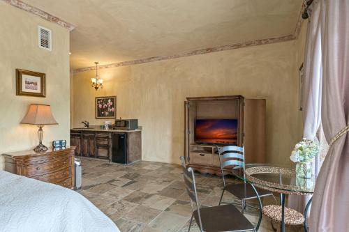 a bedroom with a bed and a tv and a table at Blanco Riverside Cottages in Blanco