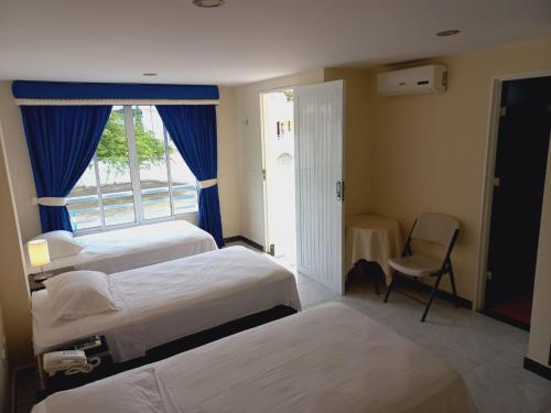 a hotel room with three beds and a window at Hotel Oasys Blue in Roldanillo