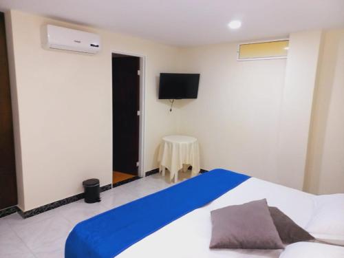 a bedroom with a bed and a tv on the wall at Hotel Oasys Blue in Roldanillo