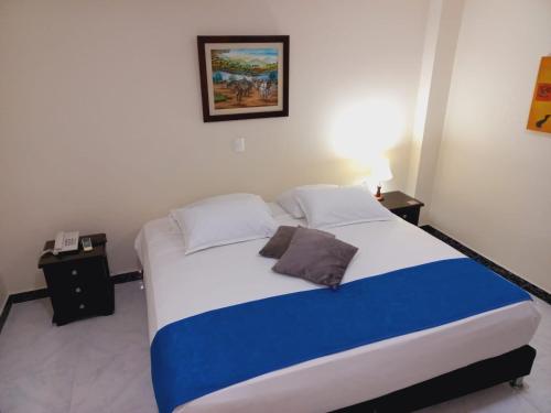 a bedroom with a large bed with blue and white sheets at Hotel Oasys Blue in Roldanillo