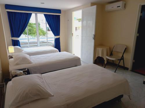 a hotel room with three beds and a window at Hotel Oasys Blue in Roldanillo