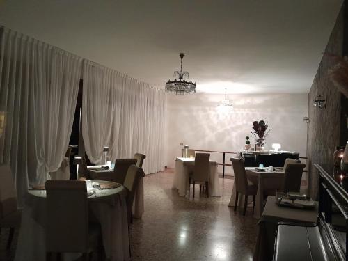 a restaurant with tables and chairs and a chandelier at Hotel Regina Yeti Bistrot in Sestola