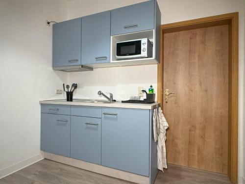 a kitchen with blue cabinets and a microwave at Ferienwohnung Plohn by Immo-Franzi in Lengenfeld