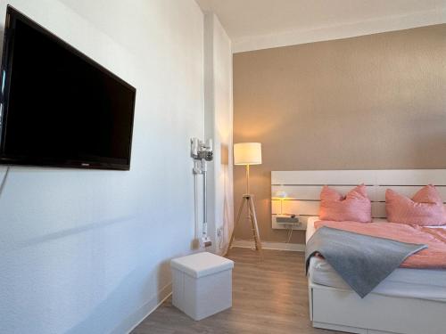 a bedroom with a bed with pink pillows and a flat screen tv at Ferienwohnung Plohn by Immo-Franzi in Lengenfeld