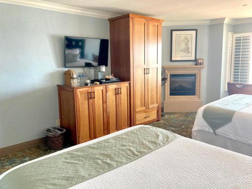 a bedroom with two beds and a cabinet and a fireplace at Blue Dolphin Inn in Cambria