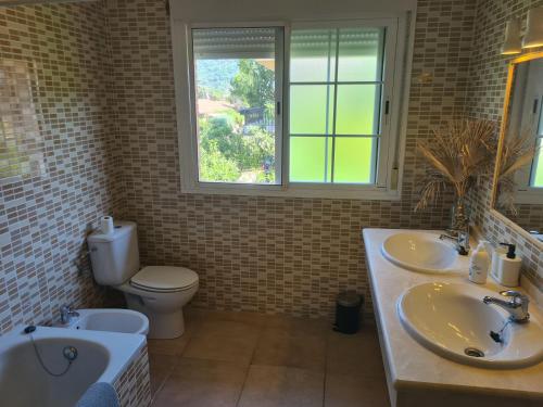 une salle de bain avec deux lavabos et un WC et une fenêtre dans l'établissement Chalet el castillo, à La Adrada