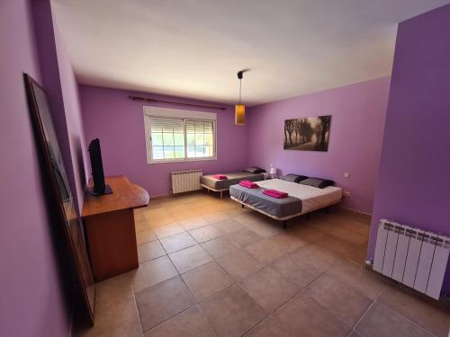 Cette chambre dispose de murs violets, d'un lit et d'un canapé. dans l'établissement Chalet el castillo, à La Adrada