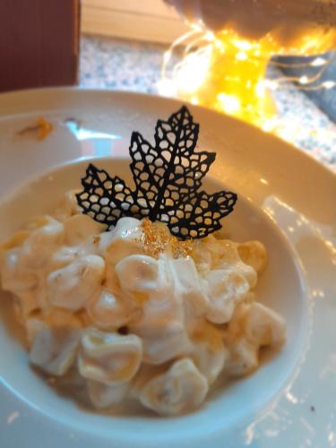 a white plate with a pasta dish with two butterflies on it at Hotel Regina Yeti Bistrot in Sestola