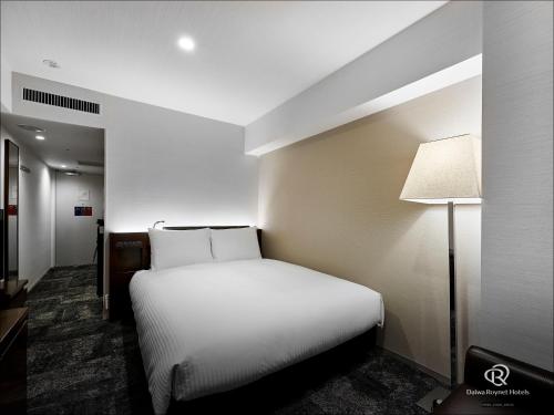 a bedroom with a white bed and a lamp at Daiwa Roynet Hotel Nishi-Shinjuku PREMIER in Tokyo