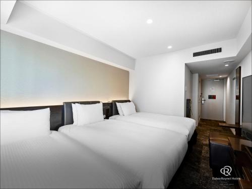 two beds in a hotel room with white pillows at Daiwa Roynet Hotel Nishi-Shinjuku PREMIER in Tokyo