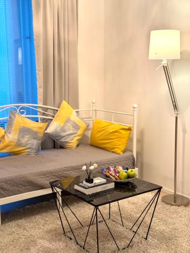 a room with a bed with a coffee table and yellow pillows at C&C Studio - Comfy Nest Near Airport & City Access in Vantaa