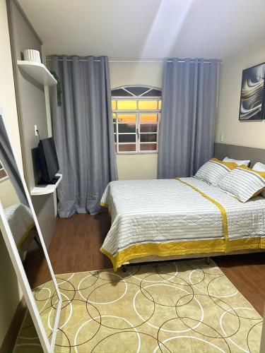 a bedroom with a bed and a television and a window at Linda casa pertinho de Tiradentes in São João del Rei