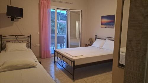 a bedroom with two beds and a window with a view at Κτήμα Καρνέση in Edipsos