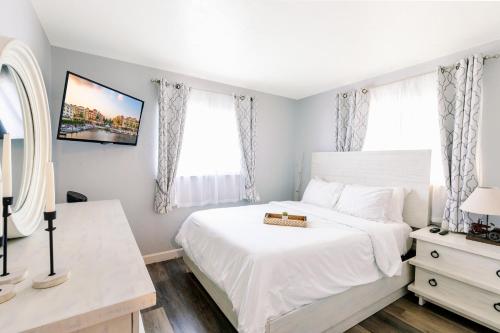 a bedroom with a white bed and two windows at Coastal Farmhouse with mini Golf, Private Beach &Spa in Naples