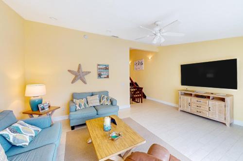 a living room with a blue couch and a flat screen tv at Palm Breeze Retreat 320 & 330 in Key Colony Beach