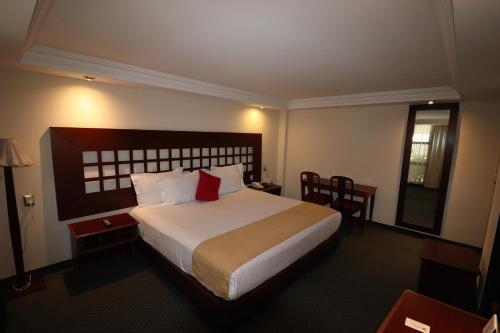 a hotel room with a large bed with a red pillow at Best Western Toluca in Toluca