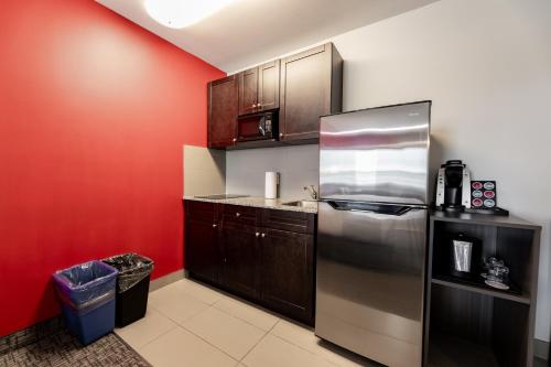 a kitchen with red walls and a stainless steel refrigerator at The Kanata by BCMInns - Hinton in Hinton
