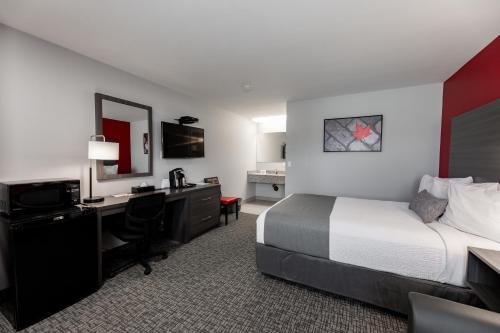 a hotel room with a bed and a desk with a computer at The Kanata by BCMInns - Hinton in Hinton