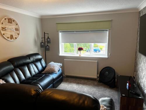a living room with a leather couch and a window at 5 minutes to Glasgow airport in Paisley