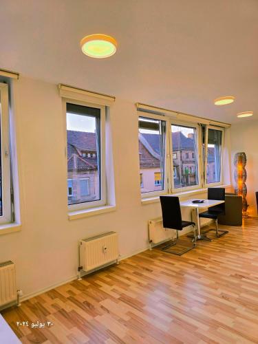 an empty room with a table and chairs and windows at B&R Apartment in Fürth in Fürth