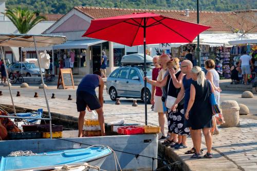 a group of people standing under a red umbrella at Nine Olives Hvar in Stari Grad