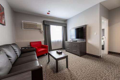 a living room with a couch and a red chair at The Kanata by BCMInns - Hinton in Hinton