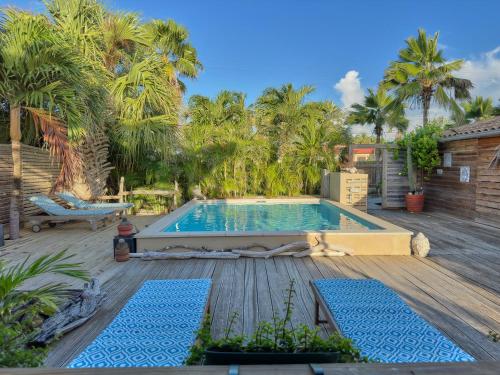 a swimming pool on a deck with palm trees at Villa Carina Apartments in Kralendijk