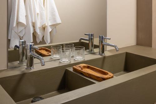 a bathroom sink with two faucets and glasses on it at Nine Olives Hvar in Stari Grad