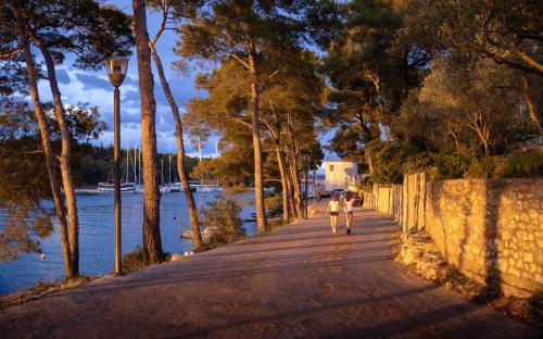 a couple walking down a sidewalk next to a body of water at Nine Olives Hvar in Stari Grad