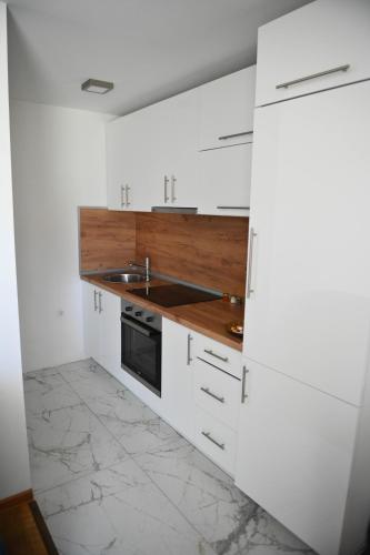 a white kitchen with a sink and a stove at Vila Mir in Banja Vrućica