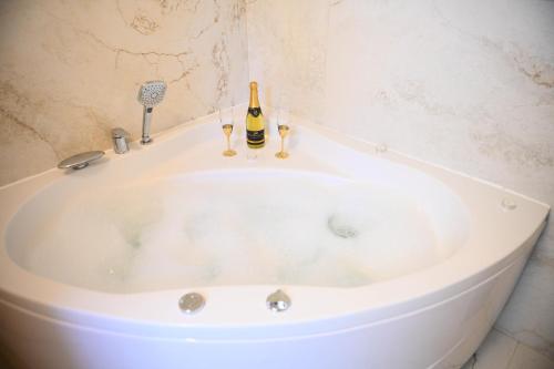 a white bath tub with two bottles of champagne at Vila Mir in Banja Vrućica