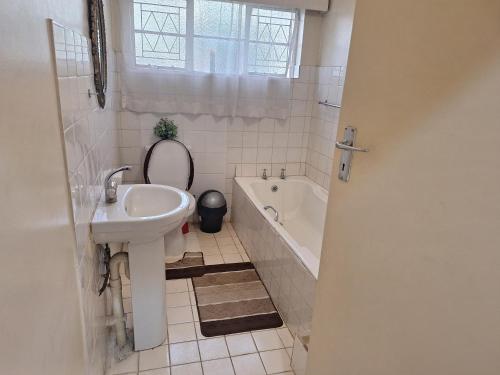 a bathroom with a sink and a toilet and a tub at Cottage - Sleeps 4 Pool & Private Parking in Harare