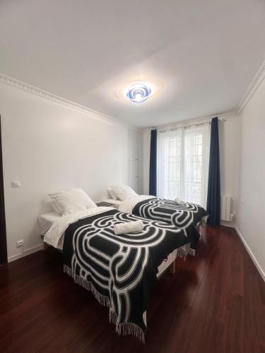 une chambre avec un lit avec une couverture noire et blanche dans l'établissement Excellent Appartement Rénové au Cœur de la Capitale, à Paris
