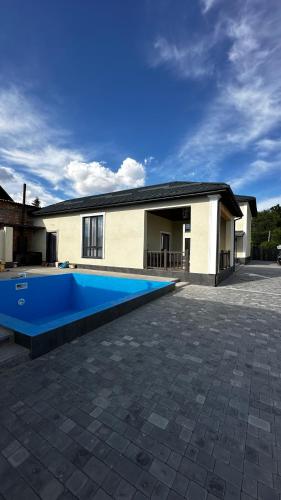 une maison avec une piscine bleue en face de celle-ci dans l'établissement Гостевой дом ORDO, à Tamchy