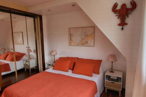 une chambre avec un grand lit avec des oreillers orange dans l'établissement Villa Roz Granit Perros-Guirec, à Saint-Quay-Perros