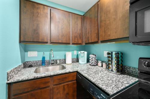 a kitchen with a sink and wooden cabinets at 1-Bedroom Haven in Murworth, Close to Medical Center in Houston