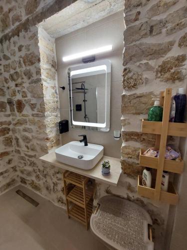 a bathroom with a white sink and a stone wall at Stone-built Villa Nesseris 80 m2 in Preveza