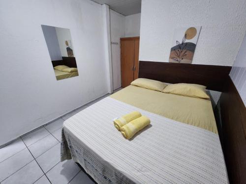 a bedroom with a bed with a yellow towel on it at Casa Aeroporto Pousada in Recife