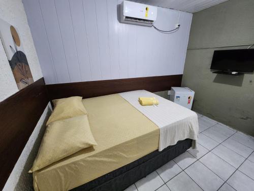 a bedroom with a bed with a yellow towel on it at Casa Aeroporto Pousada in Recife
