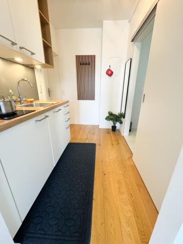 a kitchen with white cabinets and a black rug on the floor at City Comfort Inn in Linz