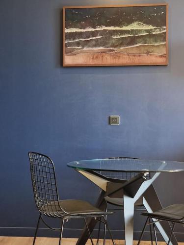 une table et des chaises dans une pièce dotée d'un mur bleu dans l'établissement Suite avec jacuzzi & terrasse vue sur l'Orb, à Béziers