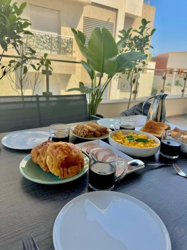 a table with plates of food on top of it at Appart avec piscine commune à Hammamet 5min de la plage in Hammamet Nord