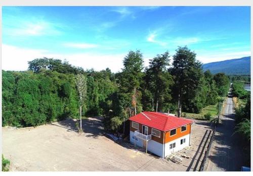 a small building with a red roof next to trees at Cabañas ROMA, entre volcanes in Puerto Varas