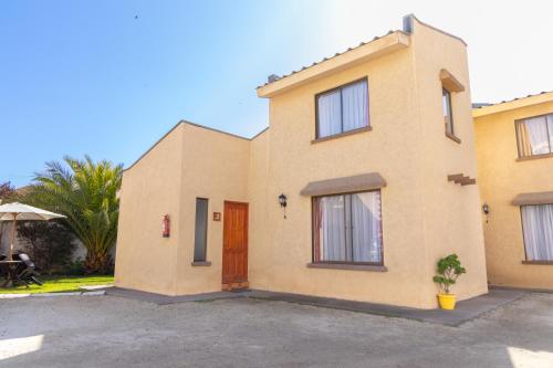 a yellow house with a door and a palm tree at De La Costa Cabañas in La Serena