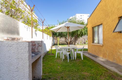 a table and chairs with an umbrella in a yard at De La Costa Cabañas in La Serena