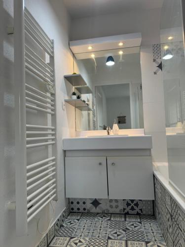 une salle de bain blanche avec un lavabo et un miroir dans l'établissement Appartement avec piscine sur le toit, à Villeurbanne