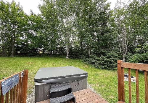 a grill sitting on a deck next to a yard at La Petite Ourse - boisé avec spa in Petite-Rivière-Saint-François