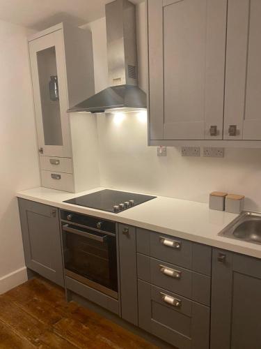 a kitchen with white cabinets and a stove top oven at Stay in Annascaul Village at Aido's in Annascaul