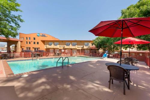 a pool with a table and a red umbrella at Best Western Kiva Inn in Fort Collins